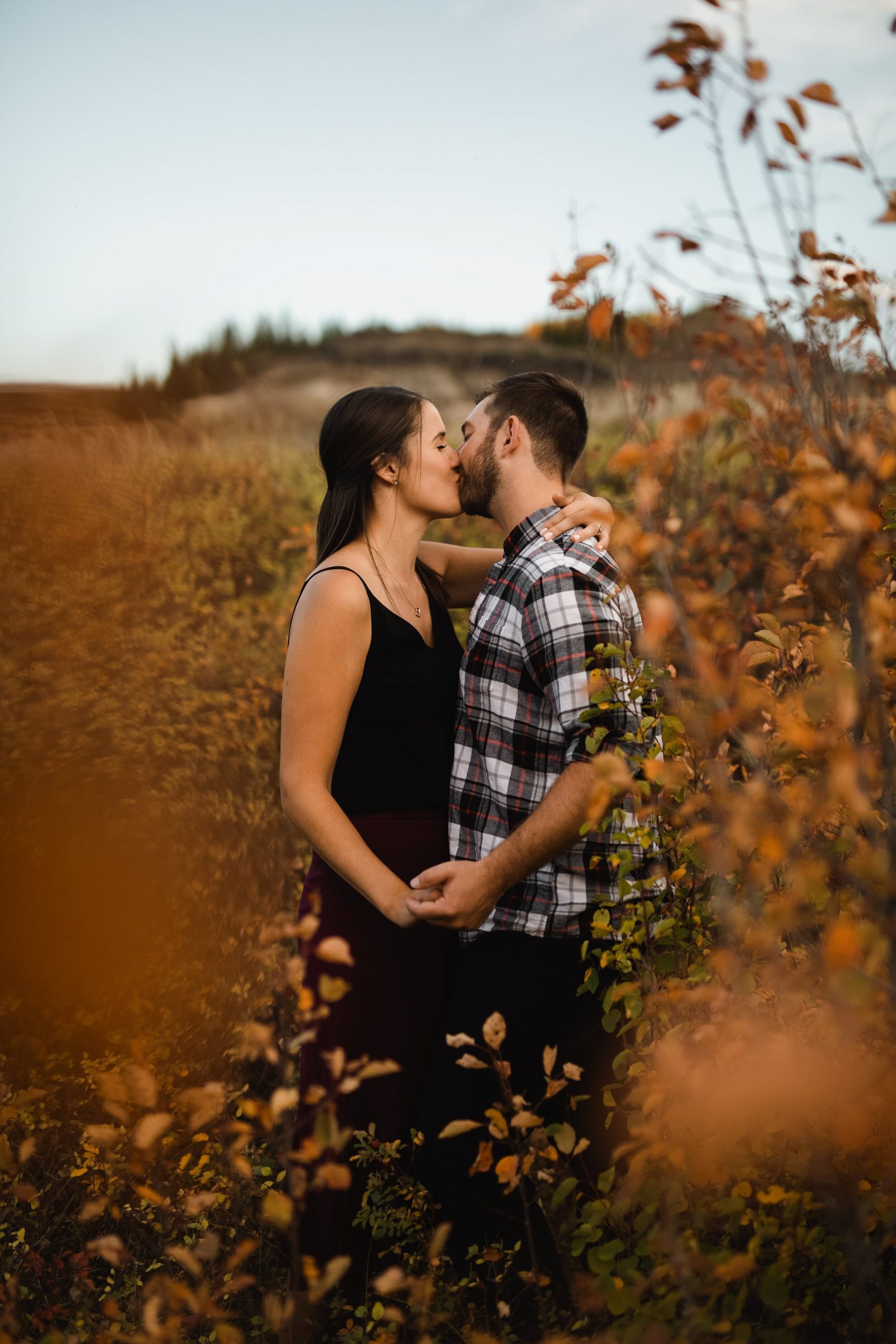 Engagement session in Drumheller, couple share intimate kiss with fall colours
